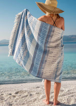 Dreamy lightweight designer Turkish towel by Bezzazan, with light blue boho design, boho girl in straw hat on the beach