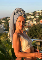 Classic minimalist Turkish towel by Bezzazan, wrapped on smiling boho girl as hair towel at sunset on a balcony