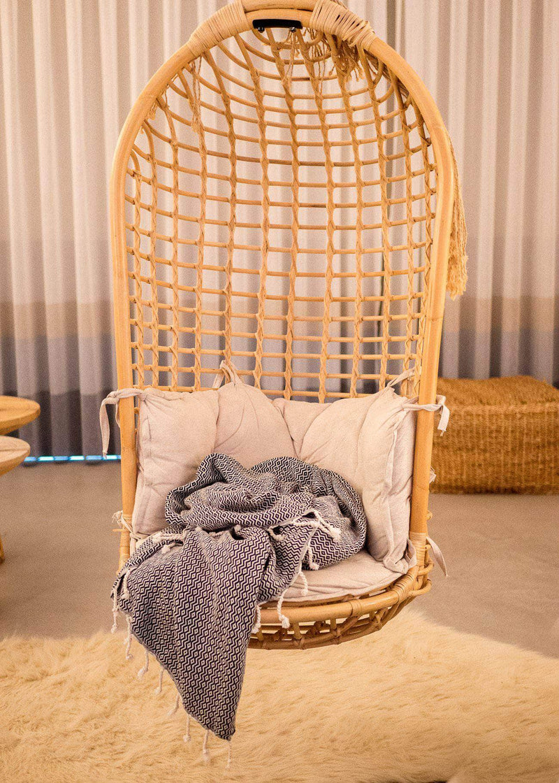 Bezzazan Aligned Throw Blanket, oversized Turkish Towel used as a modern minimalist boho decor in a hanging rattan nest chair