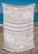 oversized turkish towel with white fringe, Flourishing XL by Bezzazan has stylish palm design, boho look, held at the beach