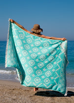 girl runs on a beach in boho hat holding Trendy Oversized Turkish towel with fringe and tribal design - Mystical Bezzazan 
