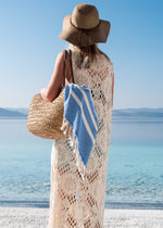 Classic Bezzazan sandfree beach towel, held by girl at the beach in beach bag, with boho hat and woven white swimsuit cover 