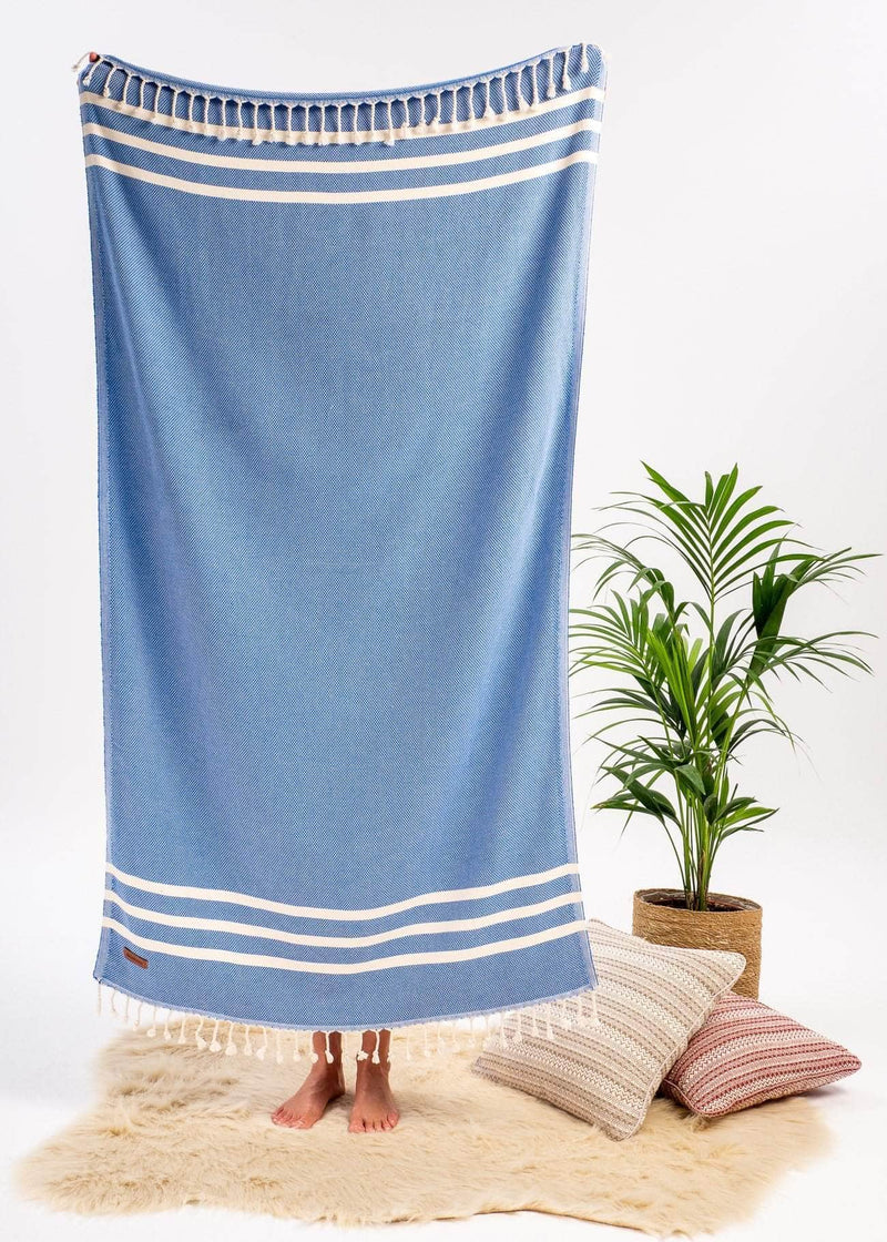 Classic Bezzazan Turkish towel as a decorative throw blanket, in a modern cozy setting, with throw pillows, plant and fur rug
