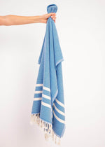 Classic Bezzazan quick-drying Turkish towel, with handloomed tassels, minimal design, held by a hand with white background