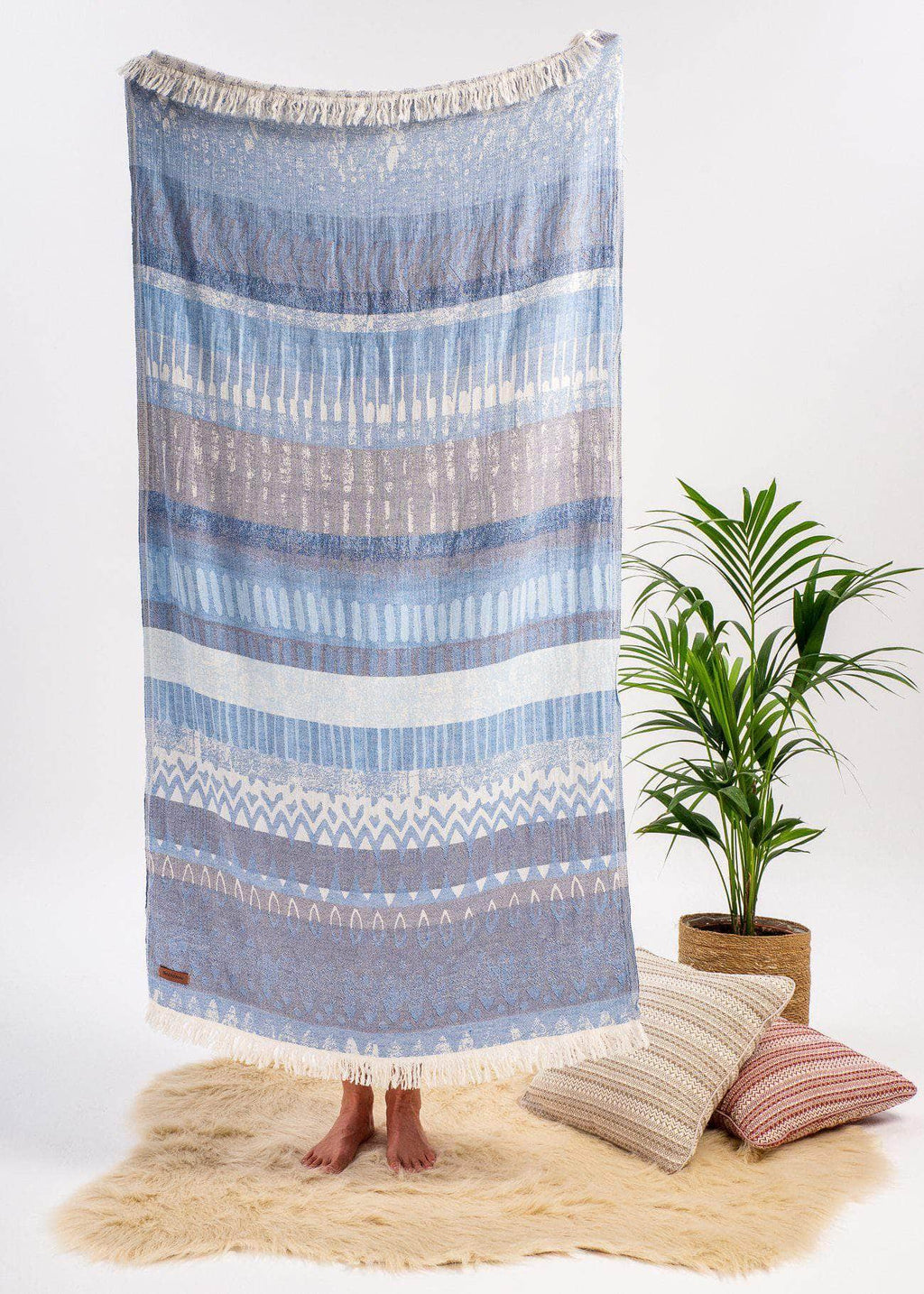 Dreamy Bezzazan minimalist stylish turkish towel, used as light throw in studio setting with throw pillows, fur rug, plant
