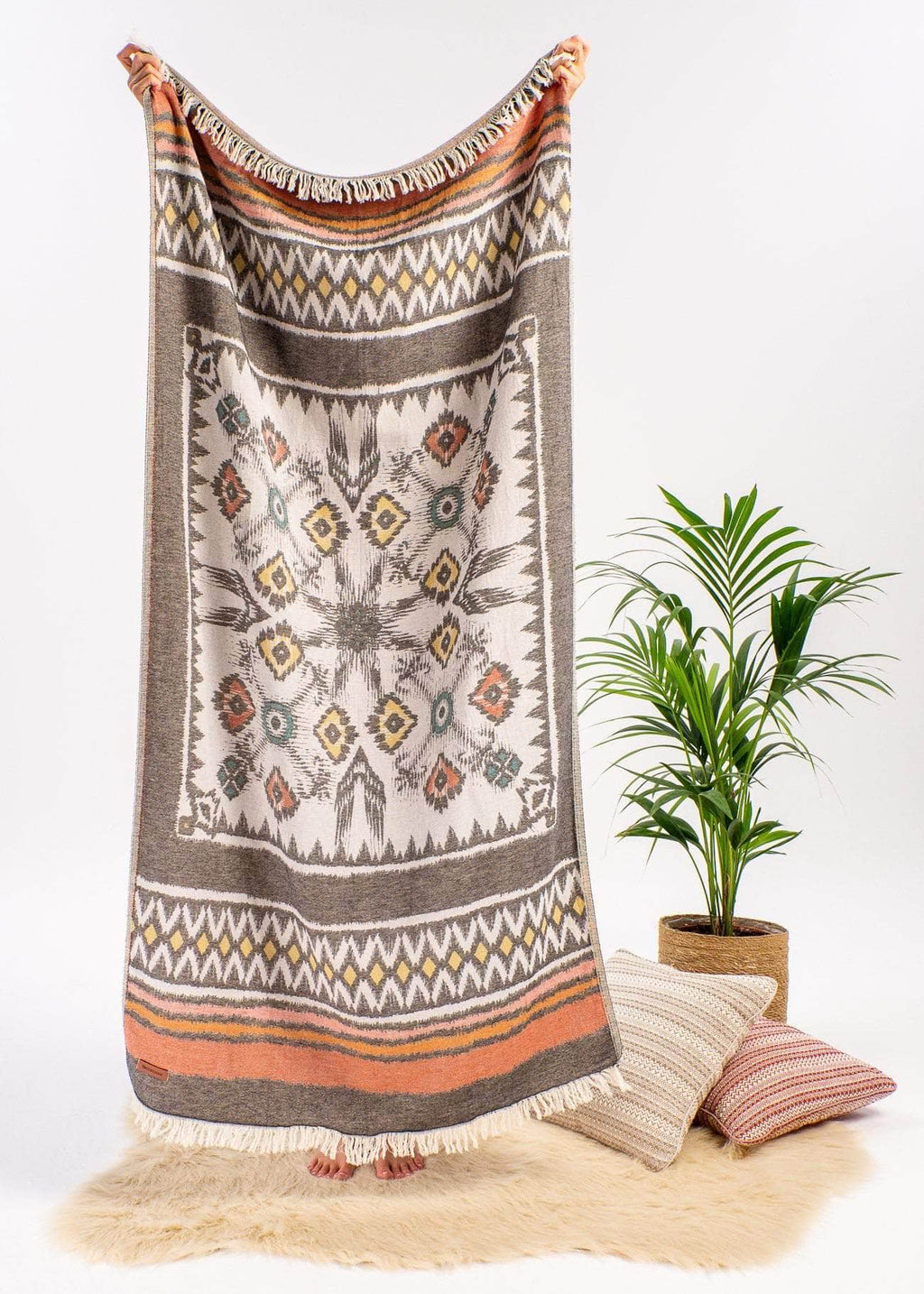 Adventurous Bezzazan Decorative Throw Blanket with fringe tribal design , boho throw pillows, plant, and white faux fur rug