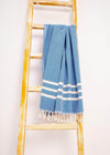 Classic Turkish towel throw blanket by Bezzazan, with handloomed tassels, used as a modern boho decor on yellow ladder