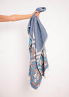 Affectionate Bezzazan premium Turkish towel, cotton, lightweight, held by hand against white wall, soft blue tribal boho chic